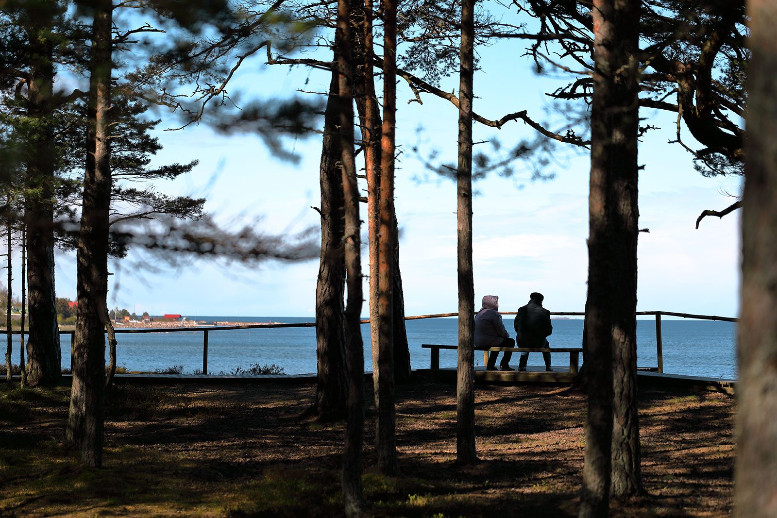 Two people sitting on bench overlooking a look and talking.