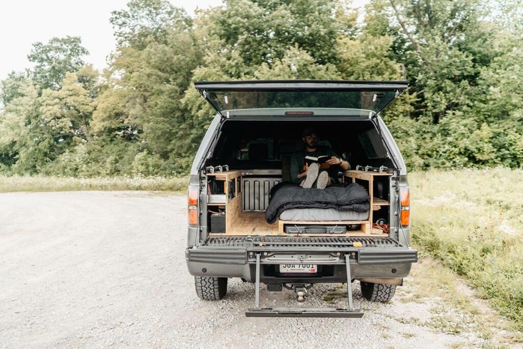 Man sitting in the back of his truck reading